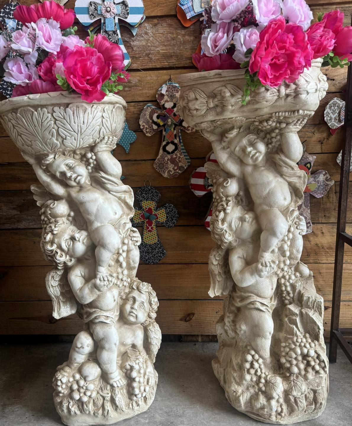 Plaster cherub pedestals set against the plank wall of the booth.