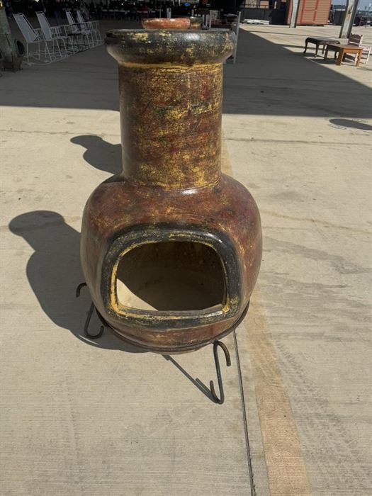 Brown glazed clay chiminea on an iron stand