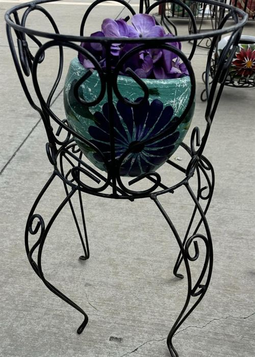Scrolled wrought iron plant stand holding a planted pot
