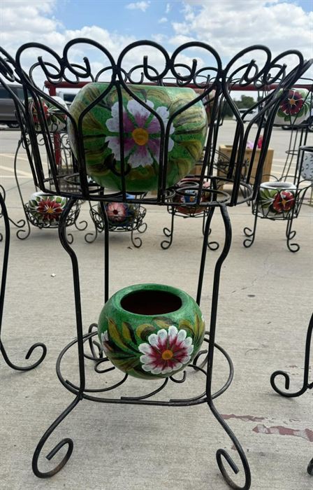A group of wrought iron plant stands holding talavera pots
